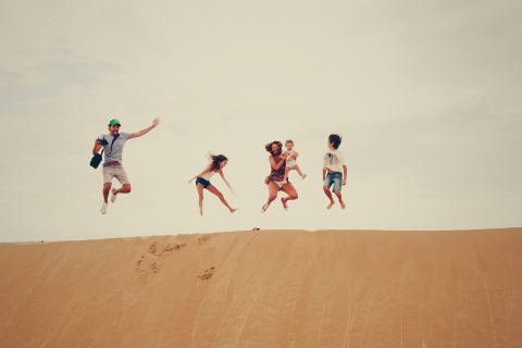 一家人在沙丘顶上齐声跳跃