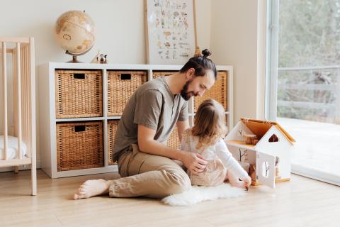 一个父亲和他的女儿一起玩玩具房子。