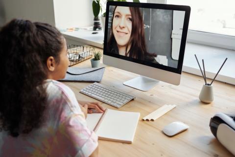 一个小女孩用家里的电脑和老师开视频会议。