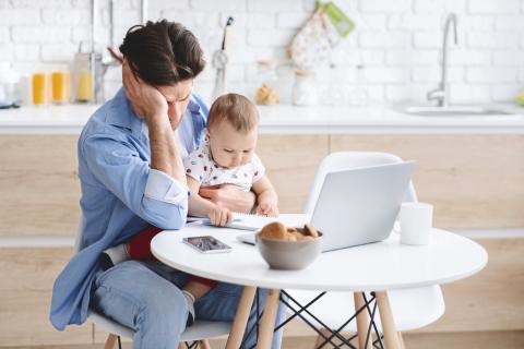 一个男人抱着他的孩子坐在电脑桌前，一脸失望。