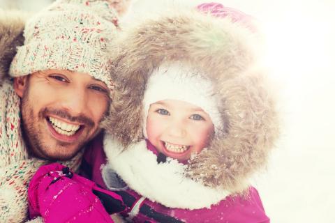 冬天，父亲和女儿在外面笑着，裹得严严实实