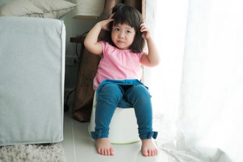 年轻女孩坐在一个便盆训练厕所。