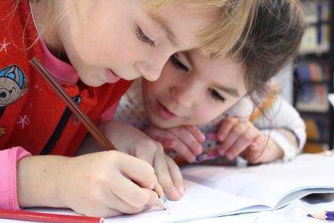 两个孩子用彩色铅笔在一起画画。