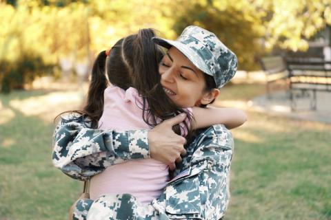 军装的妇女愉快地拥抱一个年轻女孩。
