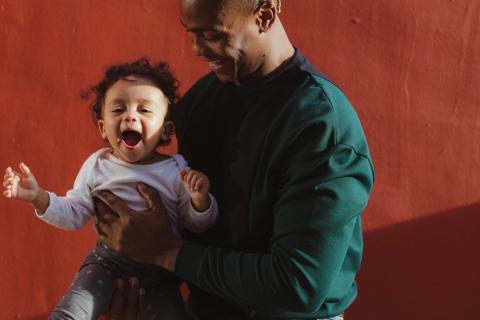 一个男人微笑着抱着一个也在微笑的婴儿。